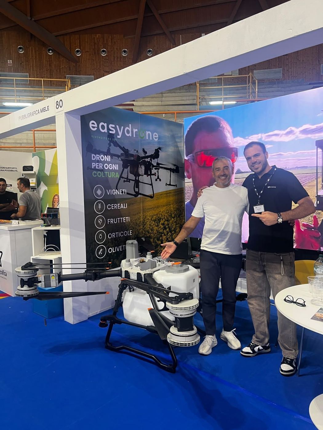Due persone allo stand EasyDrone accanto a un grande drone agricolo